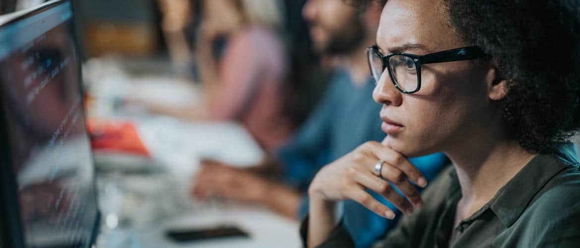 Programadora africana observa computador com muitos dados
