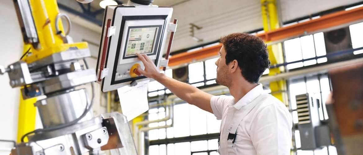 Imagem de um engenheiro mecânico operando uma máquina em uma indústria
