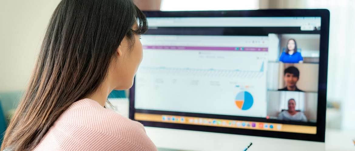 Imagem de uma empresária conversando com funcionários em uma vídeoconferência