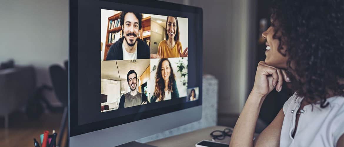 Mulher em frente ao computador conversa com amigos em uma video chamada