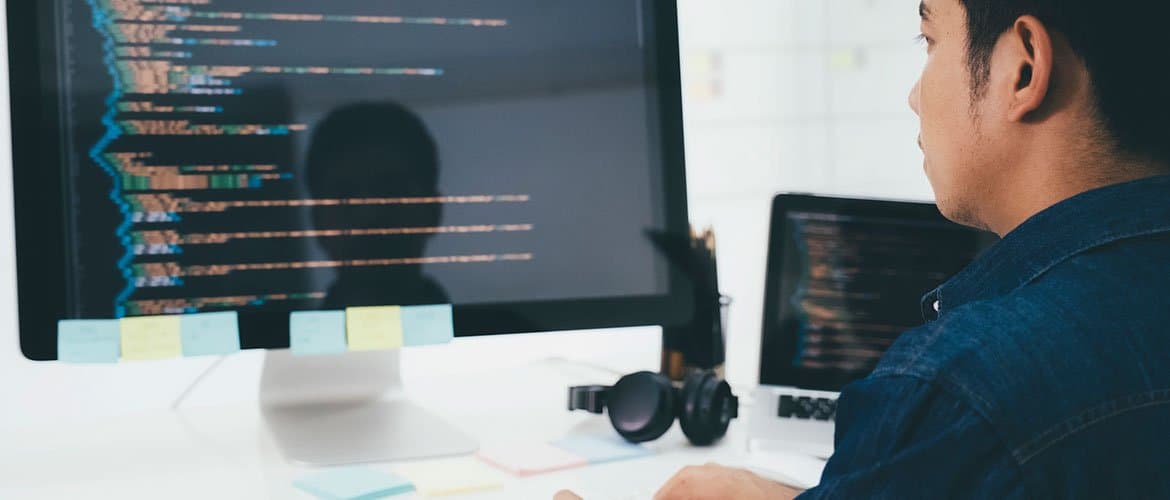 Programador olhando para um monitor com várias linguagens de programação