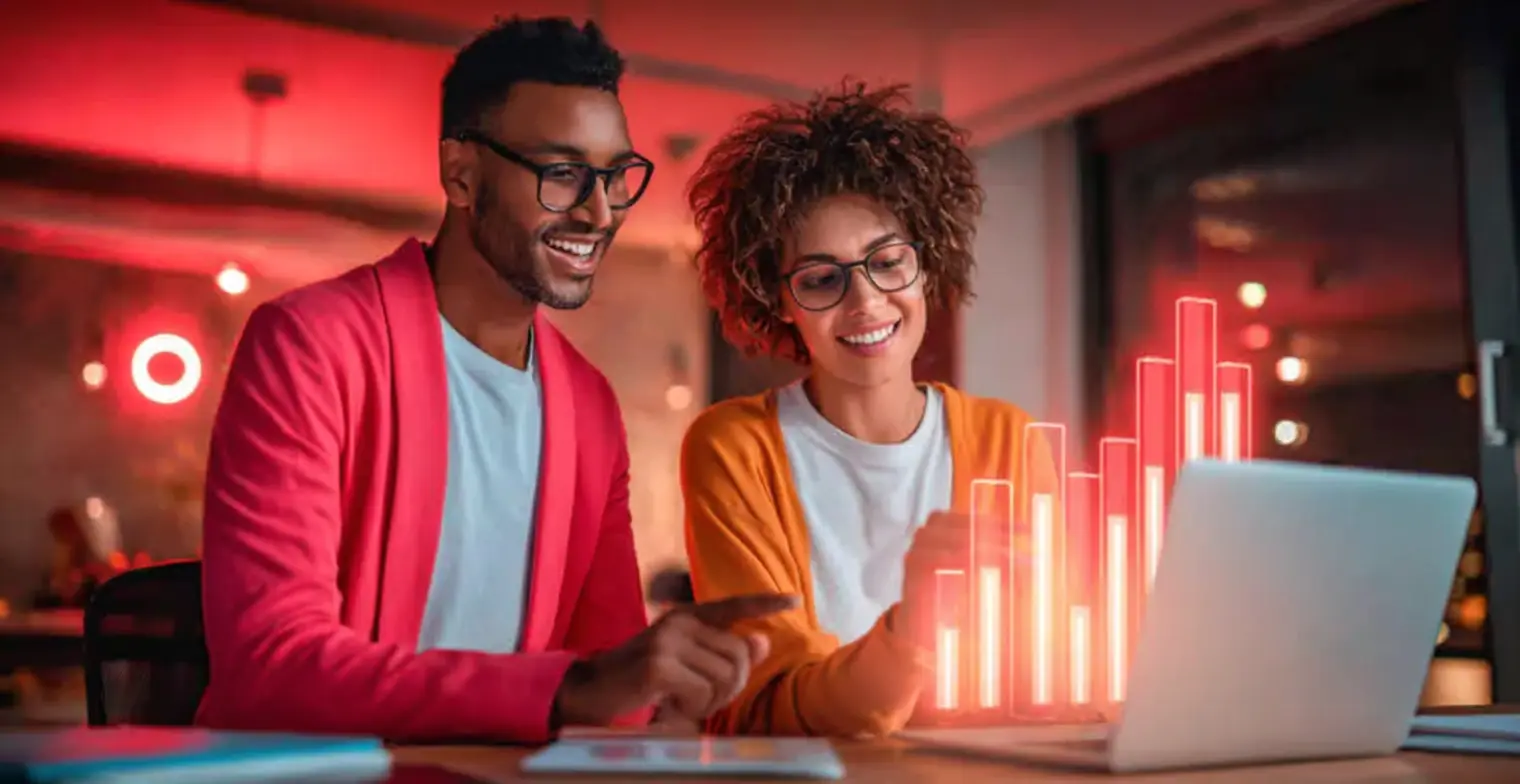 Duas pessoas analisando gráficos de negócios em um ambiente moderno, destacando a importância de real time analytics para tomada de decisões rápidas e eficazes.