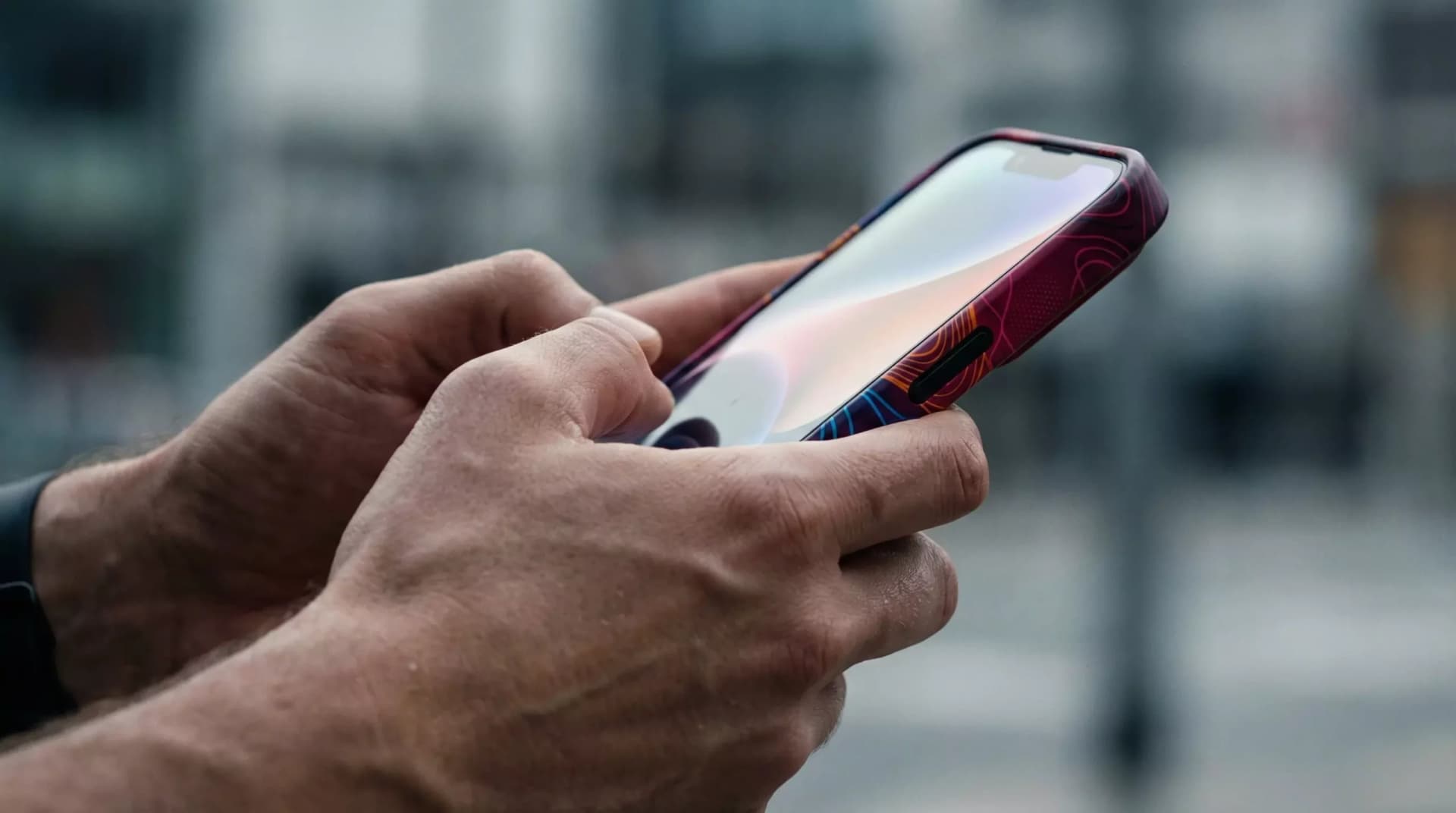 Pessoa segura um celular com as duas mãos, acena representa o uso constante de plataformas digitais, os estimulos de engajamento causado pela hiperconectividade.