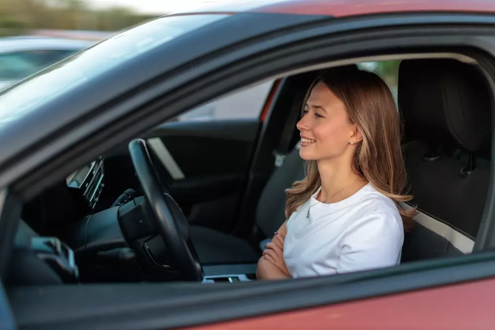 Mulher sorridente sentada em carro autônomo, destacando tecnologia de veículos autônomos e direção automatizada.