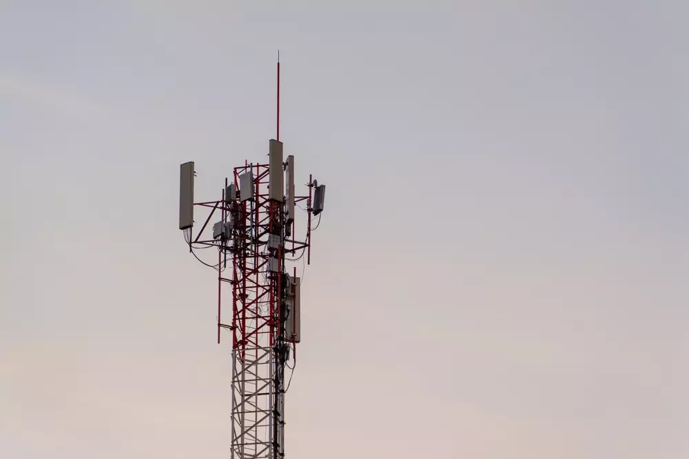 Torre de transmissão de sinal de telecomunicações contra o céu. Torre equipada com antenas e dispositivos de transmissão de dados.