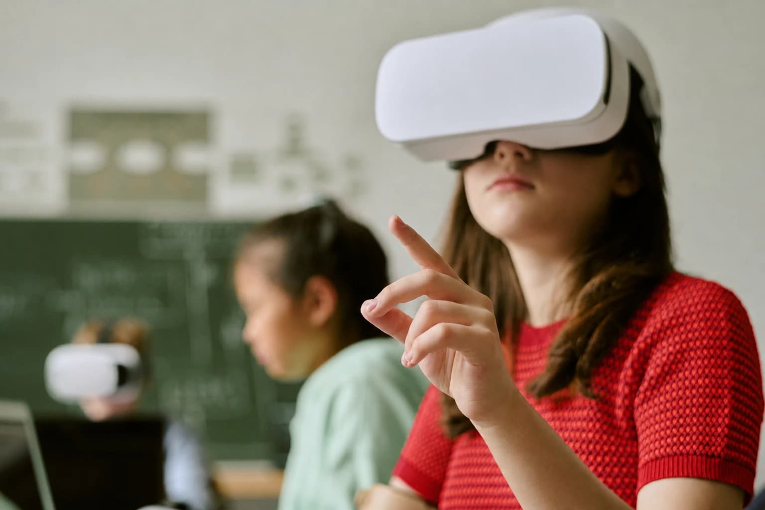 Aluna usando óculos de realidade virtual em sala de aula, com colegas ao fundo. Cena que destaca conectividade escolar e aprendizado digital com tecnologia.