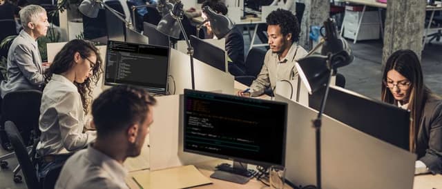 Homens e mulheres trabalhando na frente de vários computadores, usados para blockchain