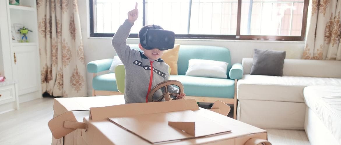 Criança com óculos de realidade virtual brinca em carro feito de papelão - futuro