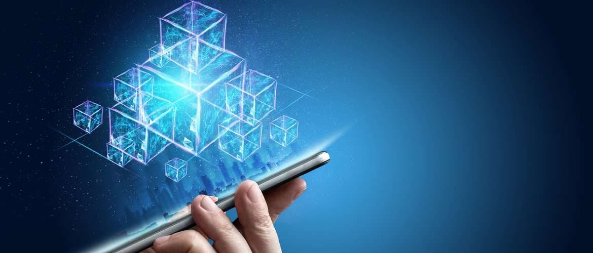 Mão segurando um smartphone com blocos de blockchain saltando da tela do aparelho
