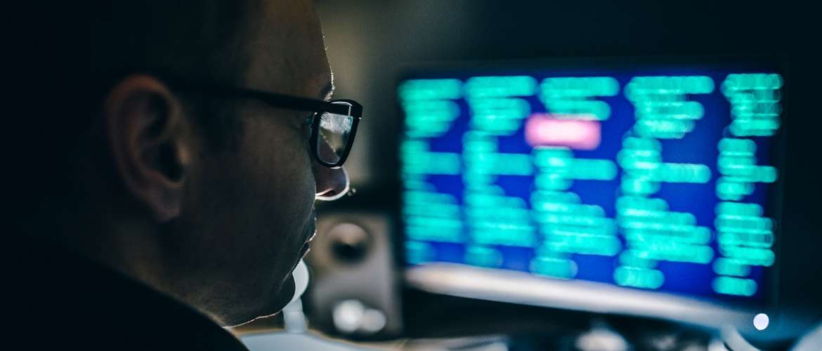 Imagem de um homem olhando para uma tela com códigos de programação