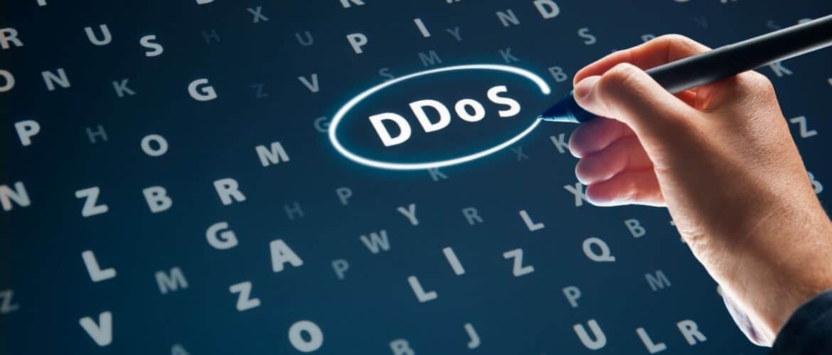 Imagem de uma mão escrevendo sobre uma tela a sigla DDoS