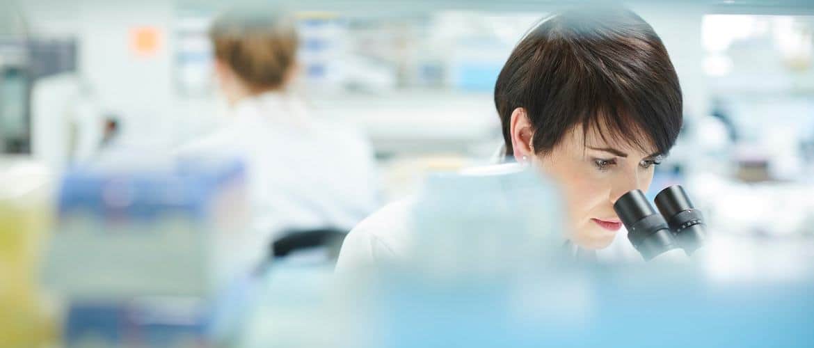 Mulher cientista analisa algo no microscópio