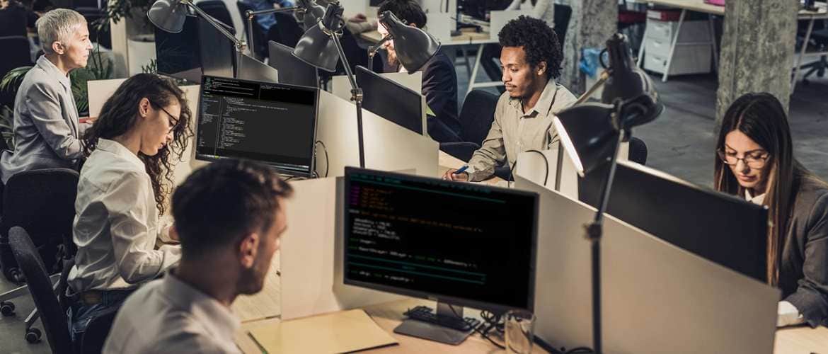 Homens e mulheres trabalhando na frente de vários computadores, usados para blockchain