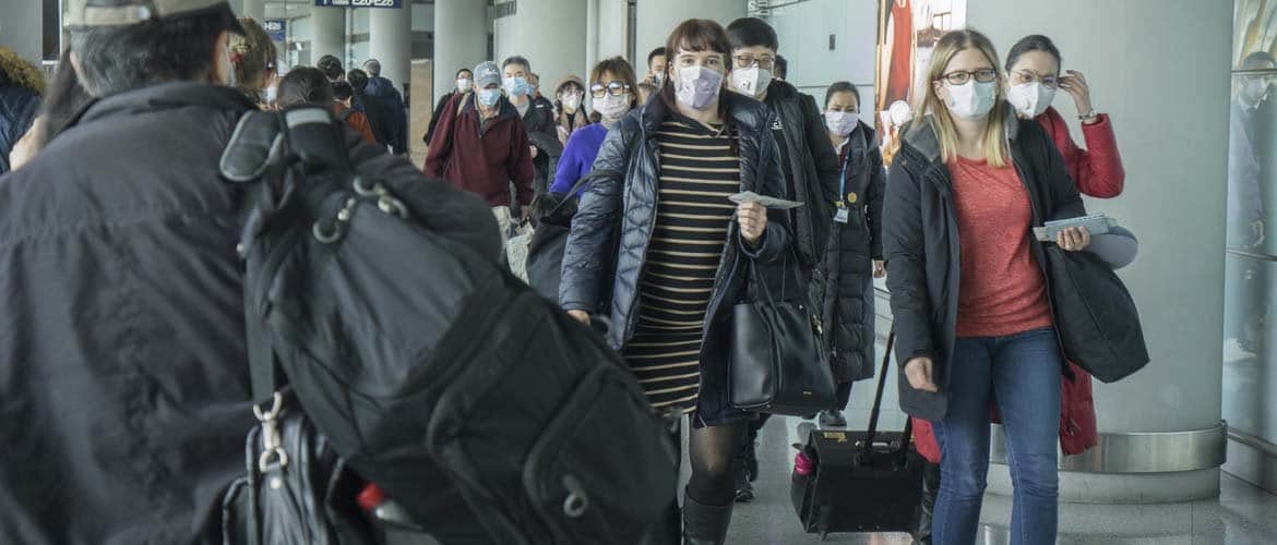 Imagem de pessoas usando máscara no corredor de um aeroporto