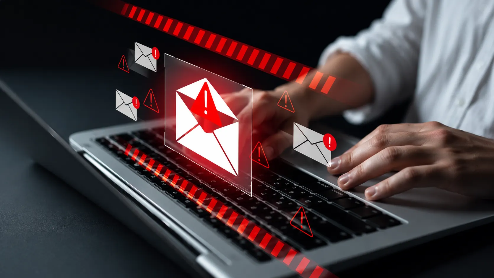 Close em um notebook com alertas visuais e ícones de risco em vermelho ao redor de um envelope de e-mail, sugerindo ameaças e vulnerabilidades de software em segurança digital.