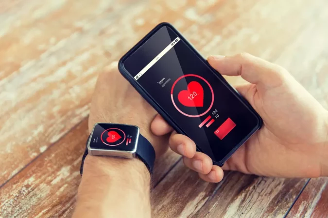 Pessoa monitorando sua pressão arterial com smartwatch e smartphone, conectado à ideia de Saúde 5.0, tecnologia e cuidados com o bem-estar.