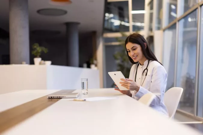 Mulher médica usando tablette no escritório moderno, promovendo novas oportunidades para mulheres na tecnologia e na saúde.